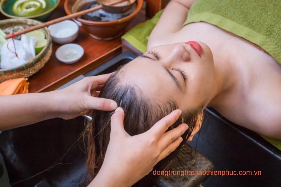 Phụ nữ massage da đầu với tinh dầu thiên nhiên để kích thích mọc tóc.